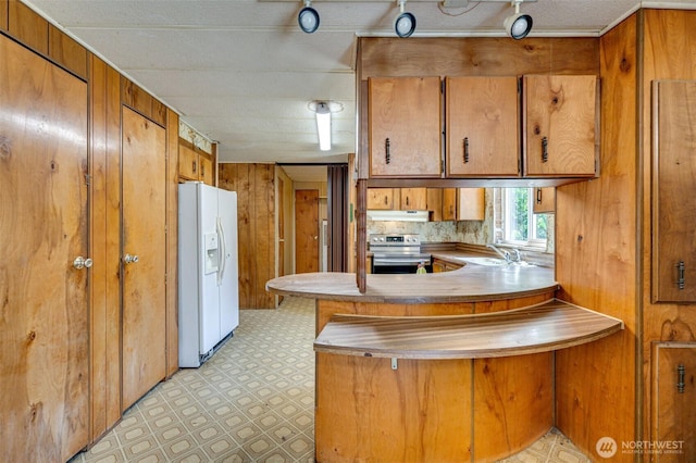 5530 Lewis River Rd, Ariel, WA 98603 - kitchen with white refrigerator with ice dispenser, stainless steel electric range oven, brown cabinets, under cabinet range hood, and a peninsula