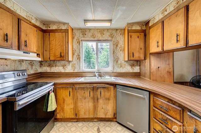 5530 Lewis River Rd, Ariel, WA 98603 - kitchen with appliances with stainless steel finishes, under cabinet range hood, wallpapered walls, a sink, and brown cabinetry