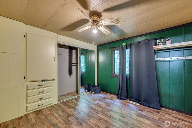5530 Lewis River Rd, Ariel, WA 98603 - unfurnished bedroom with wood finished floors, a textured ceiling, a ceiling fan, and a closet