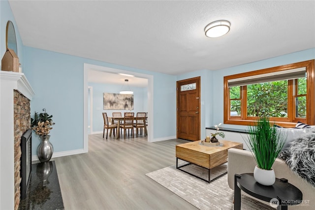 4530 240th St SW, Mountlake Terrace, WA 98043 - living room featuring a stone fireplace, wood finished floors, baseboards, and a textured ceiling