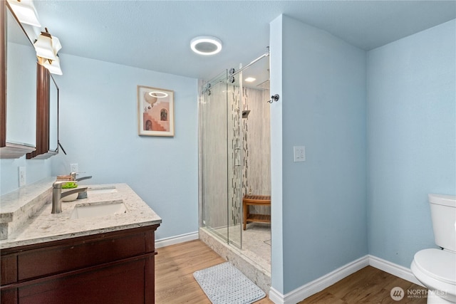 4530 240th St SW, Mountlake Terrace, WA 98043 - bathroom featuring toilet, double vanity, wood finished floors, a stall shower, and baseboards