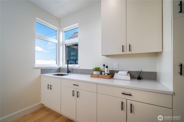 8004 39th Ave SW, Seattle, WA 98136 - kitchen featuring a sink, light wood-style floors, light countertops, and white cabinets