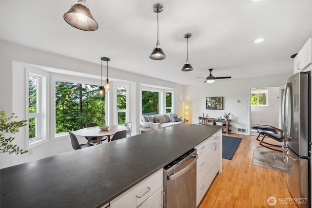 1188 Island Dr, Lummi Island, WA 98262 - kitchen featuring stainless steel appliances, white cabinetry, dark countertops, light wood finished floors, and ceiling fan