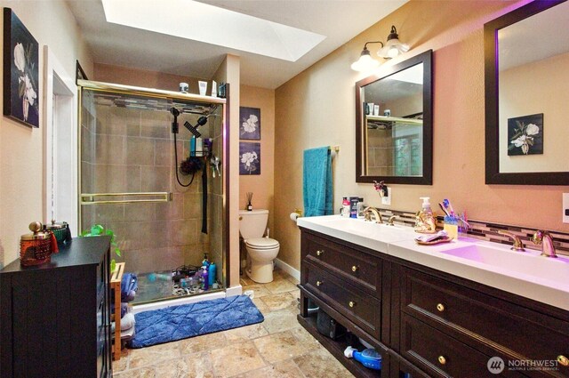 17521 25th Street Ct E, Lake Tapps, WA 98391 - bathroom with a skylight, toilet, double vanity, a stall shower, and stone finish flooring