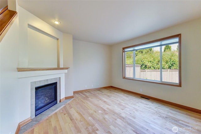 19402 NE 68th Way, Redmond, WA 98052 - unfurnished living room with wood finished floors, baseboards, a tiled fireplace, and recessed lighting