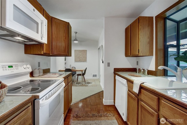 9512 1st Ave NE Unit 402, Seattle, WA 98115 - kitchen with white appliances, tile countertops, a sink, brown cabinetry, and baseboards
