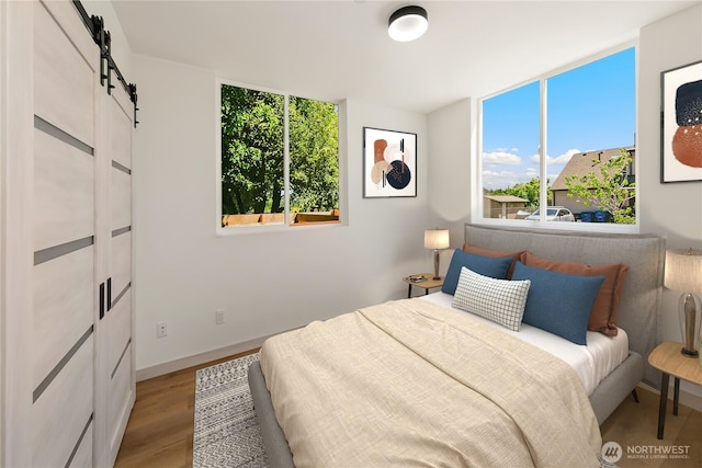 4306 S Holden St, Seattle, WA 98118 - bedroom featuring a barn door, wood finished floors, and baseboards