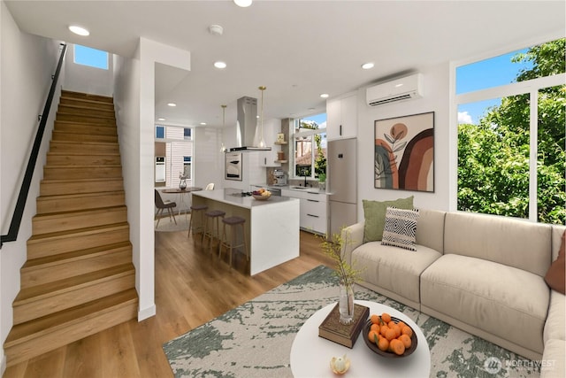 4306 S Holden St, Seattle, WA 98118 - living room featuring a wall mounted air conditioner, plenty of natural light, stairway, light wood-type flooring, and recessed lighting