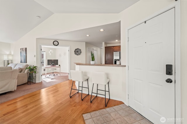 2143 Hammond Ave Unit E10, Dupont, WA 98327 - kitchen with stainless steel refrigerator with ice dispenser, a breakfast bar, vaulted ceiling, light wood-type flooring, and open floor plan