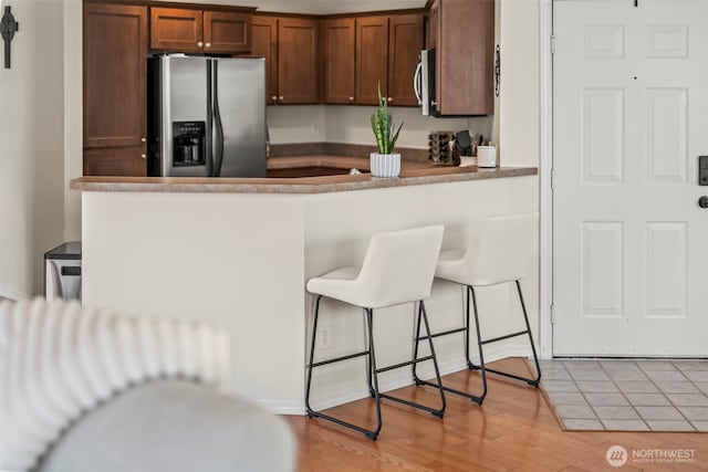 2143 Hammond Ave Unit E10, Dupont, WA 98327 - kitchen with appliances with stainless steel finishes, light wood finished floors, a breakfast bar, and a peninsula