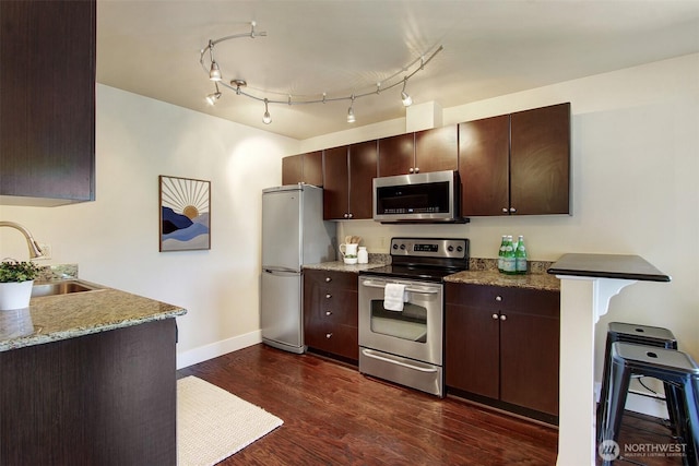 120 NW 39th St Unit 406, Seattle, WA 98107 - kitchen with stainless steel appliances, a sink, dark brown cabinetry, baseboards, and dark wood-type flooring