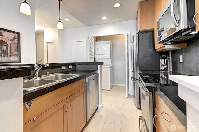 16141 Cleveland St Unit 611, Redmond, WA 98052 - kitchen with stacked washer / drying machine, appliances with stainless steel finishes, a sink, dark countertops, and light tile patterned floors