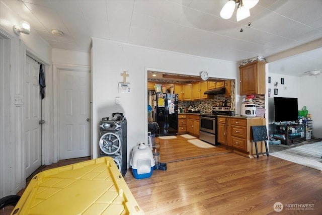 412 Maple Ct, Toppenish, WA 98948 - kitchen featuring stainless steel stove, black fridge with ice dispenser, under cabinet range hood, light wood finished floors, and brown cabinets