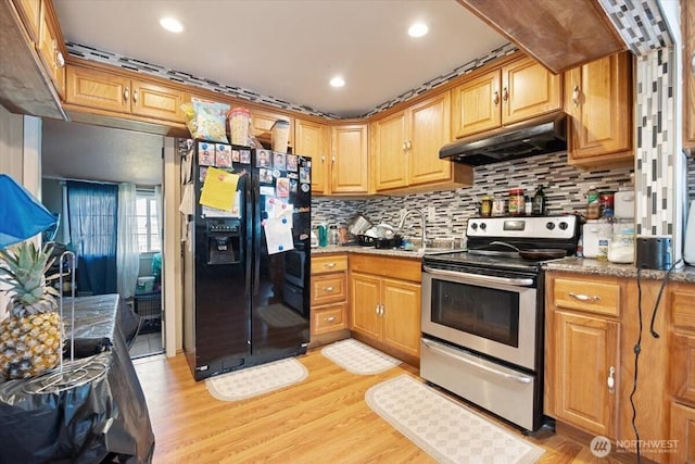 412 Maple Ct, Toppenish, WA 98948 - kitchen with black fridge with ice dispenser, stainless steel electric range, under cabinet range hood, light wood-style flooring, and decorative backsplash