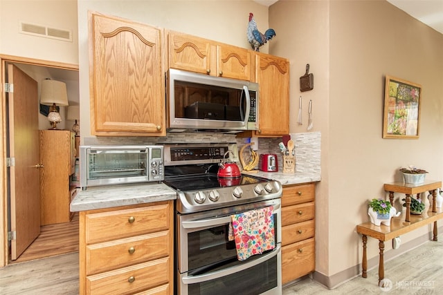 23 Majesty Way, Port Angeles, WA 98362 - kitchen with appliances with stainless steel finishes, light wood-style flooring, and decorative backsplash