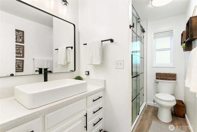 3827 90th Ave E, Edgewood, WA 98371 - bathroom featuring wood finished floors, toilet, vanity, a shower stall, and baseboards