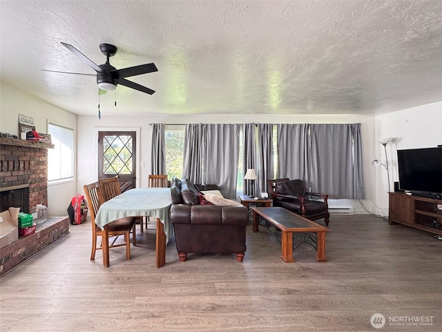 81 Robbins Rd, Sequim, WA 98382 - living area with a textured ceiling, wood finished floors, ceiling fan, and a brick fireplace