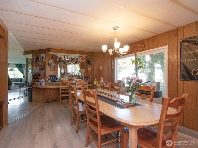 81 Robbins Rd, Sequim, WA 98382 - dining space featuring wooden walls, a chandelier, light wood-style flooring, vaulted ceiling, and plenty of natural light