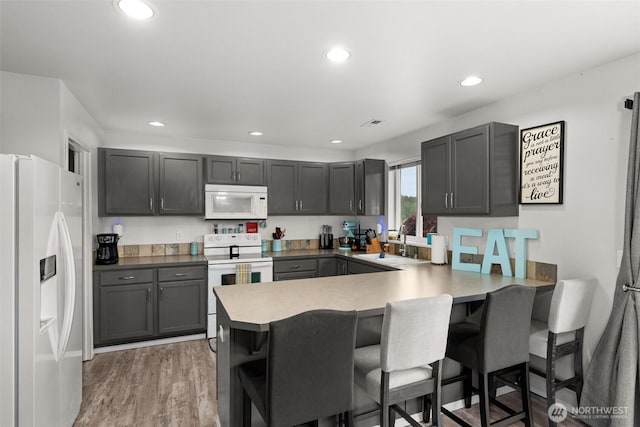 167 Goldmyer Dr, Chehalis, WA 98532 - kitchen featuring white appliances, a sink, a peninsula, a kitchen bar, and recessed lighting