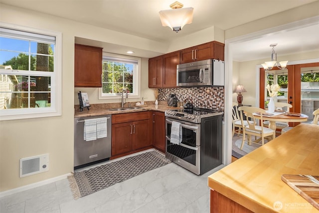 8724 Main St, Edmonds, WA 98026 - kitchen featuring appliances with stainless steel finishes, a sink, tasteful backsplash, a chandelier, and baseboards