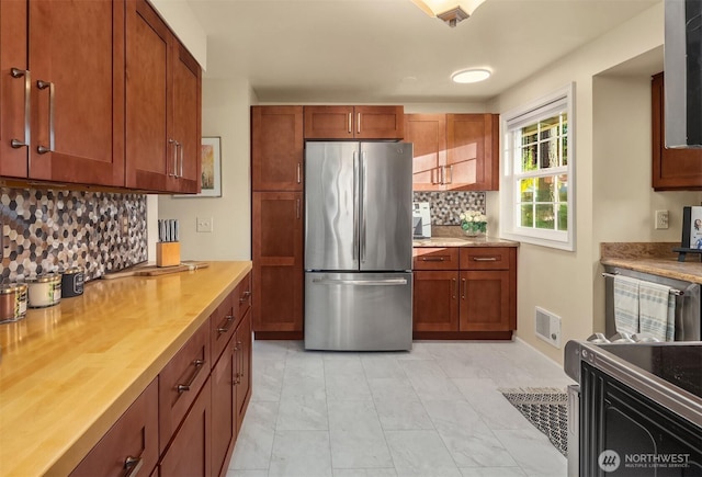 8724 Main St, Edmonds, WA 98026 - kitchen featuring freestanding refrigerator, light countertops, decorative backsplash, light marble finish flooring, and brown cabinetry