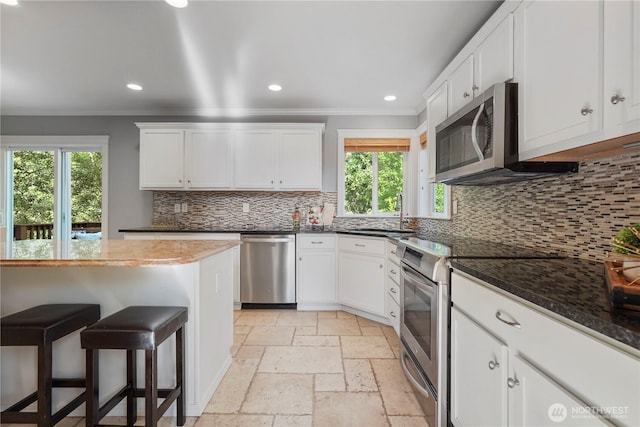 13374 SE 308th Ct, Auburn, WA 98092 - kitchen with stainless steel appliances, a sink, crown molding, a kitchen bar, and stone tile floors