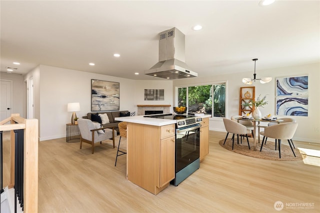 5134 S Wallace St, Seattle, WA 98178 - kitchen featuring island exhaust hood, stainless steel range with electric cooktop, light wood-style floors, light brown cabinetry, and baseboards