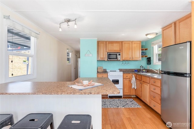 7535 Sunset Dr, Blaine, WA 98230 - kitchen featuring stainless steel appliances, light wood-style flooring, open shelves, a breakfast bar area, and light brown cabinetry