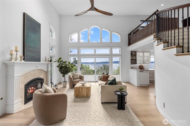 26045 Marine View Dr S, Des Moines, WA 98198 - living room with ceiling fan, a premium fireplace, light wood-type flooring, a towering ceiling, and stairway
