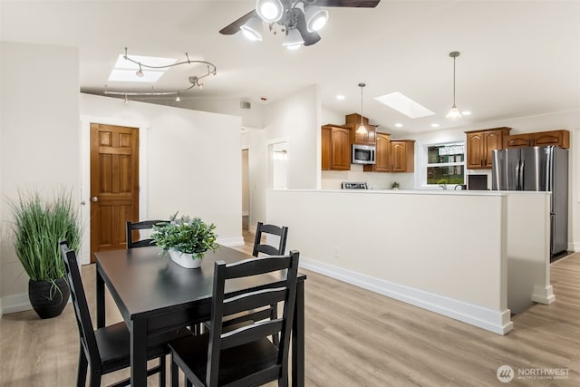 110 E Sea Breeze Dr, Grapeview, WA 98546 - dining area with vaulted ceiling, light wood-style flooring, a skylight, a ceiling fan, and baseboards