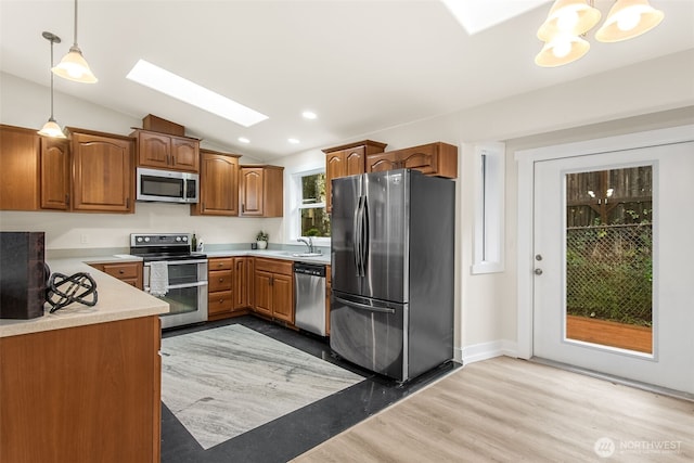 110 E Sea Breeze Dr, Grapeview, WA 98546 - kitchen featuring stainless steel appliances, a skylight, a sink, light wood-style floors, and hanging light fixtures