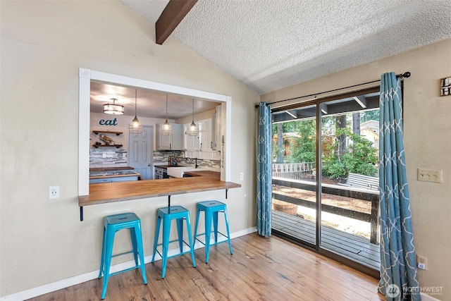 268 Kingsway W, Bremerton, WA 98312 - kitchen featuring backsplash, wood finished floors, a textured ceiling, a kitchen bar, and decorative light fixtures