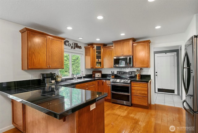 34821 NE Gable Ave, La Center, WA 98629 - kitchen with stainless steel appliances, a peninsula, brown cabinetry, a breakfast bar, and recessed lighting