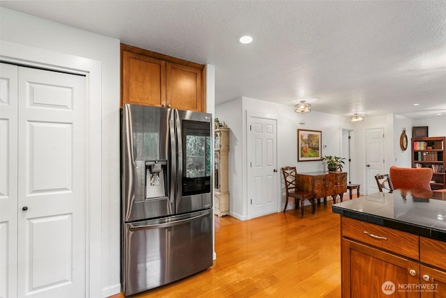 34821 NE Gable Ave, La Center, WA 98629 - kitchen with stainless steel fridge, brown cabinetry, light wood-type flooring, a textured ceiling, and tile countertops