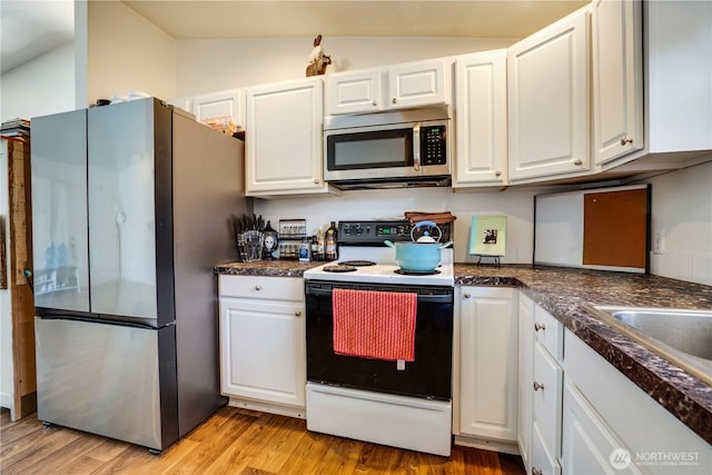 641 3rd Ave S, Kent, WA 98032 - kitchen featuring stainless steel appliances, white cabinets, light wood-type flooring, dark countertops, and vaulted ceiling