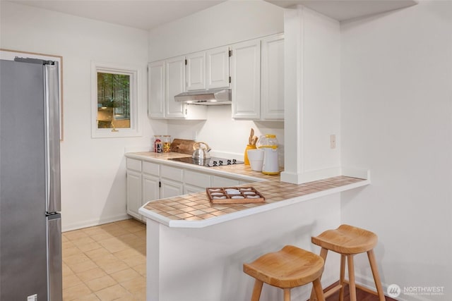 16822 SE 26th St, Bellevue, WA 98008 - kitchen featuring freestanding refrigerator, a peninsula, white cabinetry, and a breakfast bar