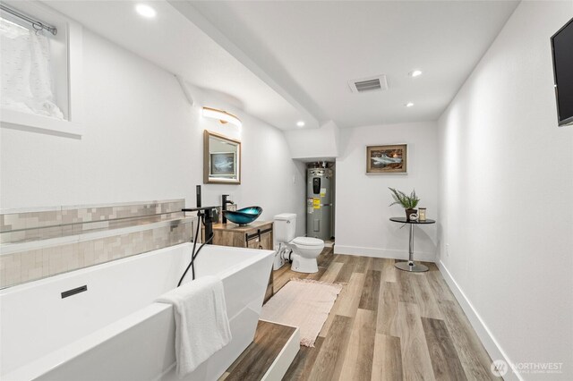3161 Locust Ave, Bellingham, WA 98225 - full bathroom with toilet, a freestanding tub, electric water heater, wood finished floors, and recessed lighting