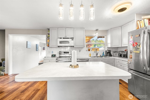 1209 Dundee Dr, Cosmopolis, WA 98537 - kitchen featuring stainless steel appliances, a sink, light countertops, decorative backsplash, and light wood-style floors