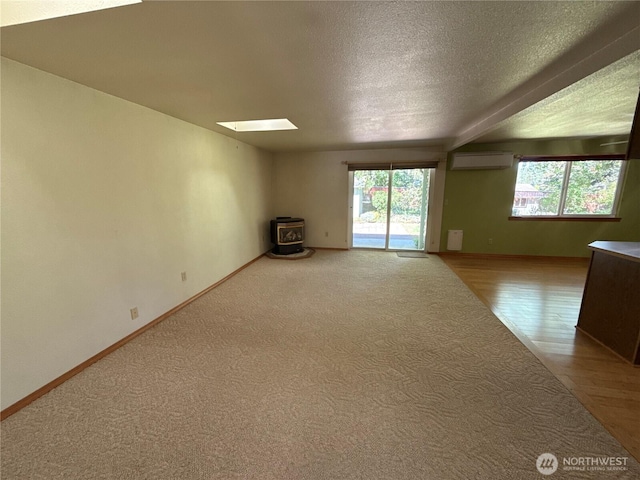 4882 Laura Ln SE, Port Orchard, WA 98367 - empty room featuring an AC wall unit, a wood stove, a skylight, a textured ceiling, and baseboards