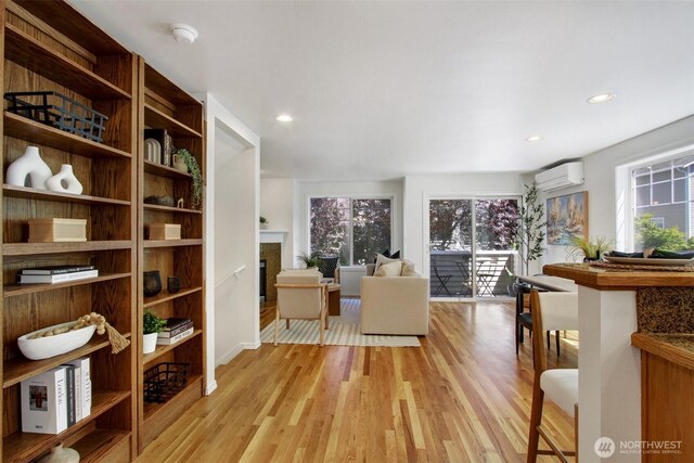 8540 Midvale Ave N Unit A, Seattle, WA 98103 - living area featuring an AC wall unit, light wood-type flooring, a glass covered fireplace, and recessed lighting