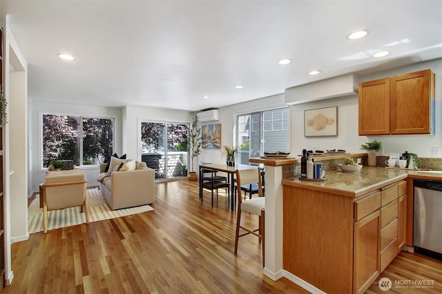 8540 Midvale Ave N Unit A, Seattle, WA 98103 - kitchen with stainless steel dishwasher, a wall mounted AC, light wood-style flooring, a breakfast bar area, and recessed lighting