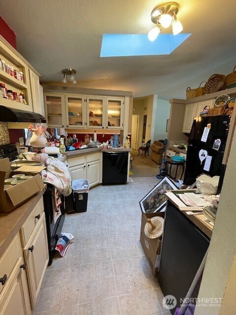 11410 127th St E Unit 185, Puyallup, WA 98374 - kitchen featuring black appliances, a skylight, glass insert cabinets, open shelves, and light tile patterned floors