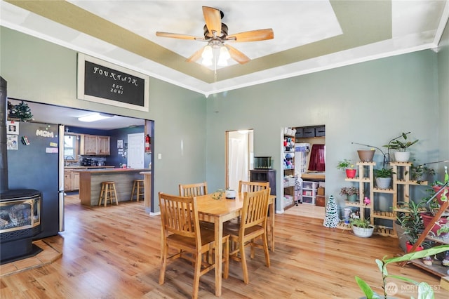 108 2nd St SE, Rainier, WA 98576 - dining space with a wood stove, a tray ceiling, light wood-type flooring, a ceiling fan, and a towering ceiling