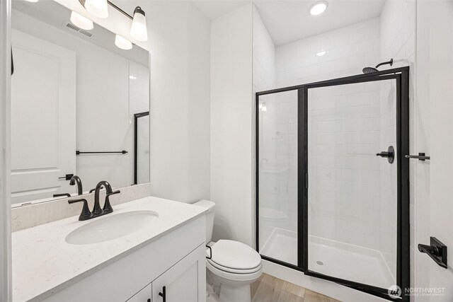 20523 97th Ave E Unit 25, Graham, WA 98338 - full bath with toilet, vanity, a shower stall, wood finished floors, and recessed lighting