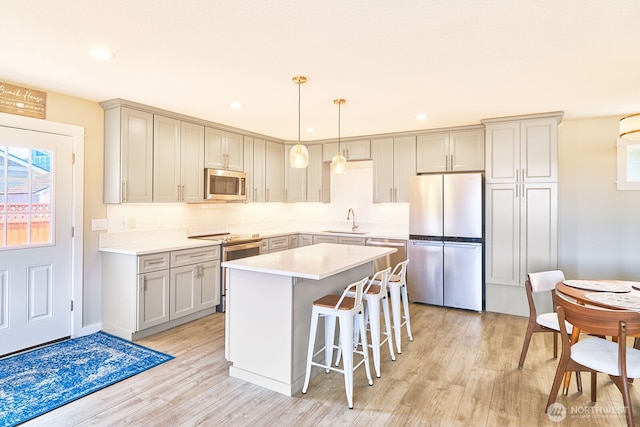 31810 I St, Ocean Park, WA 98640 - kitchen featuring stainless steel appliances, light wood-style flooring, backsplash, a kitchen island, and a breakfast bar area