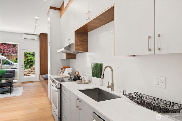 633 13th Ave E, Seattle, WA 98102 - kitchen featuring stainless steel electric range oven, an AC wall unit, a sink, light wood-style flooring, and light countertops