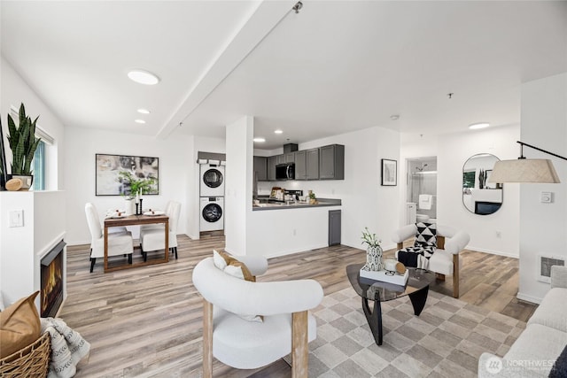 3717 California Ave SW Unit 304, Seattle, WA 98116 - living area with stacked washer and clothes dryer, light wood-style flooring, recessed lighting, and baseboards