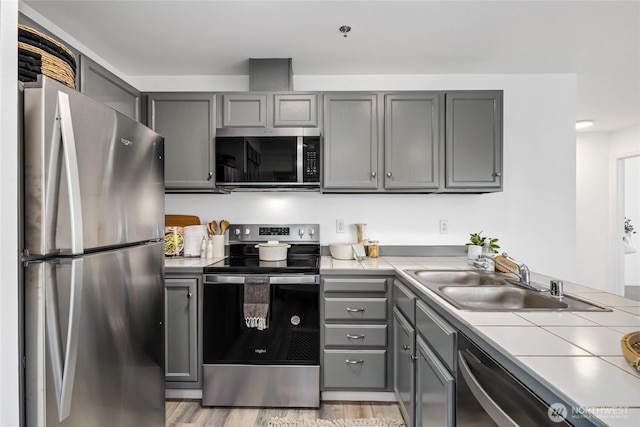 3717 California Ave SW Unit 304, Seattle, WA 98116 - kitchen featuring stainless steel appliances, gray cabinets, tile counters, and a sink