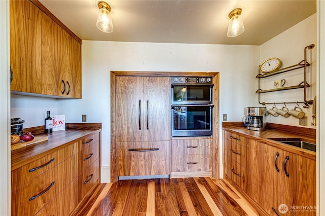 1716 E 4th St, Port Angeles, WA 98362 - kitchen featuring double oven, dark wood-style floors, brown cabinetry, a sink, and wooden counters