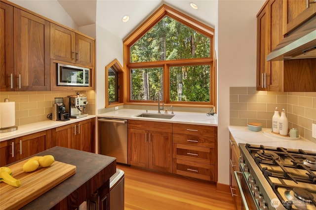 815 Carefree Way, Friday Harbor, WA 98250 - kitchen featuring appliances with stainless steel finishes, vaulted ceiling, exhaust hood, brown cabinets, and light wood-style flooring